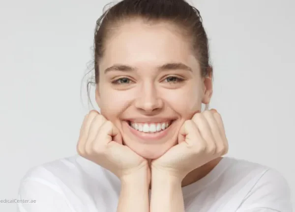A cheerful young woman smiling brightly outdoors, representing the benefits of smiling more often.