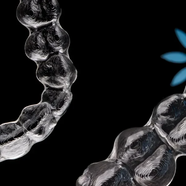 Close-up of a person gently placing Invisalign aligners over their teeth, showing slight discomfort.