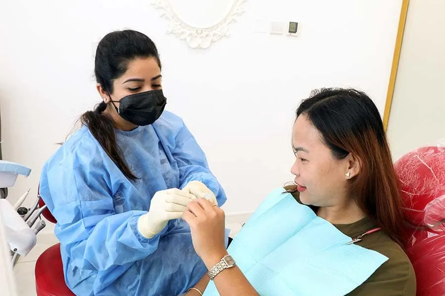 An orthodontist adjusting braces on a patient's teeth.